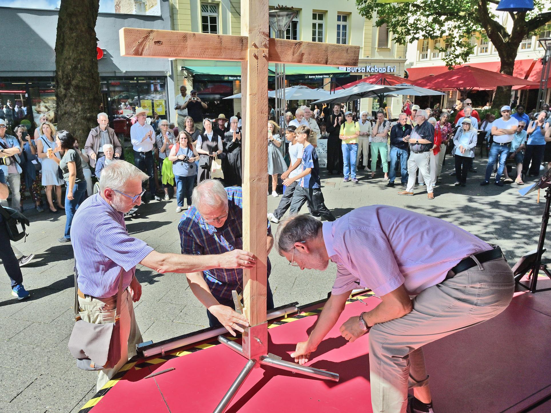 Auf dem Neumarkt werden die vier Kreuzteile, die die Teilnehmer der vier Wallprozessionen getragen haben, zusammengesetzt.